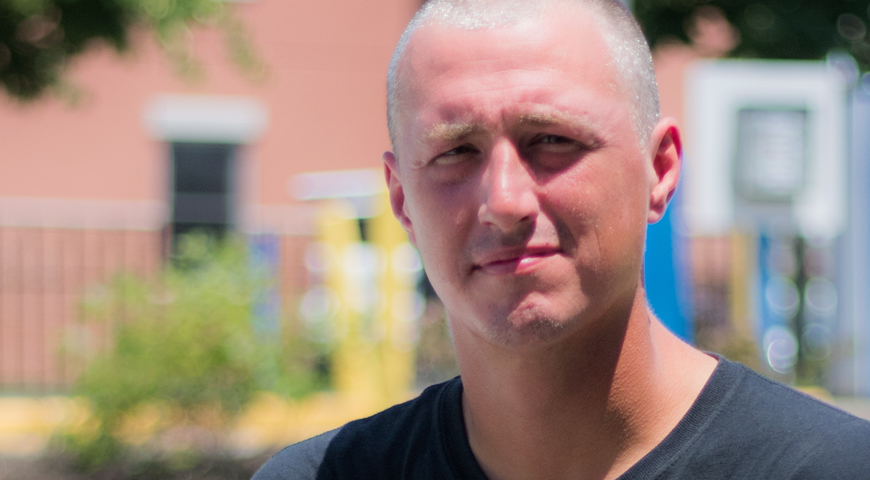 Close up of a man with a relaxed expression wearing a t-shirt, with wrinkles on his forehead, nose and jaw.